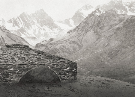 Circular Shelter Featuring Local Stone and Charred Wooden Shingles in Mountainous Terrain  