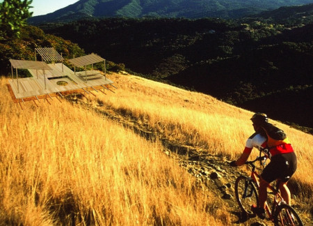 Charred Wooden Shingles and Recycled Timber Create a Versatile Bike Rest Stop in Nature